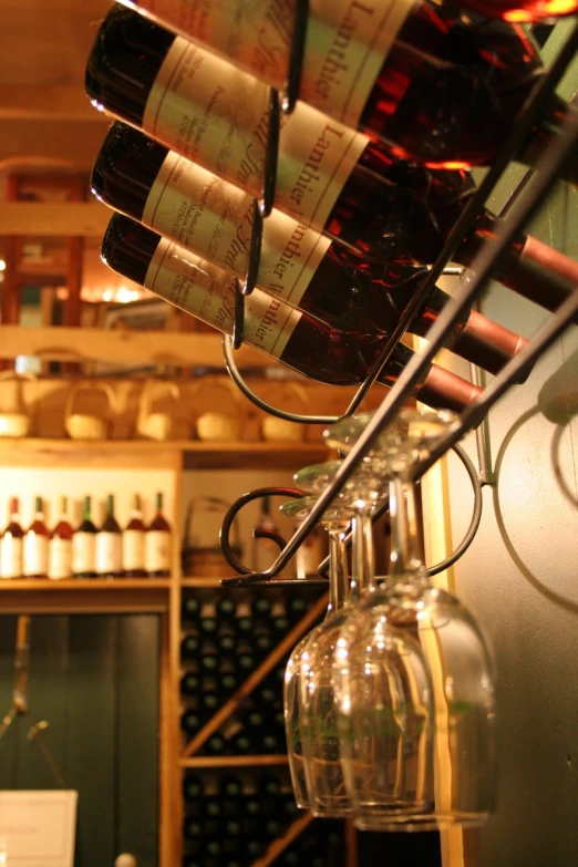 many bottles of wine and glasses hanging on a rack