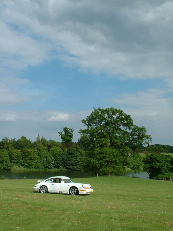 the white car is parked in a field near trees