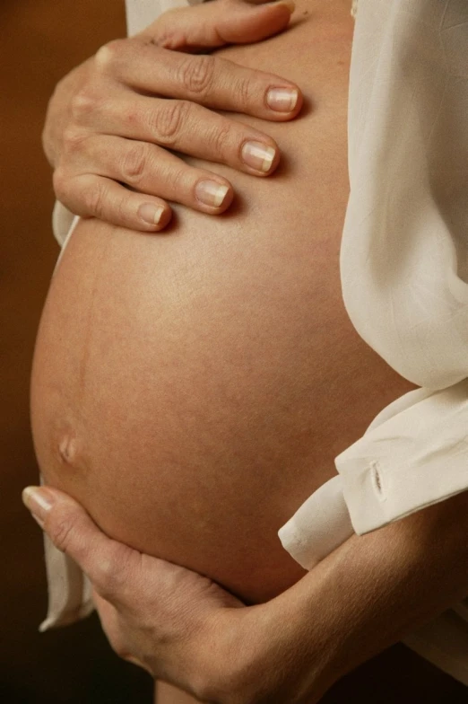 a pregnant woman holding her stomach up to the side