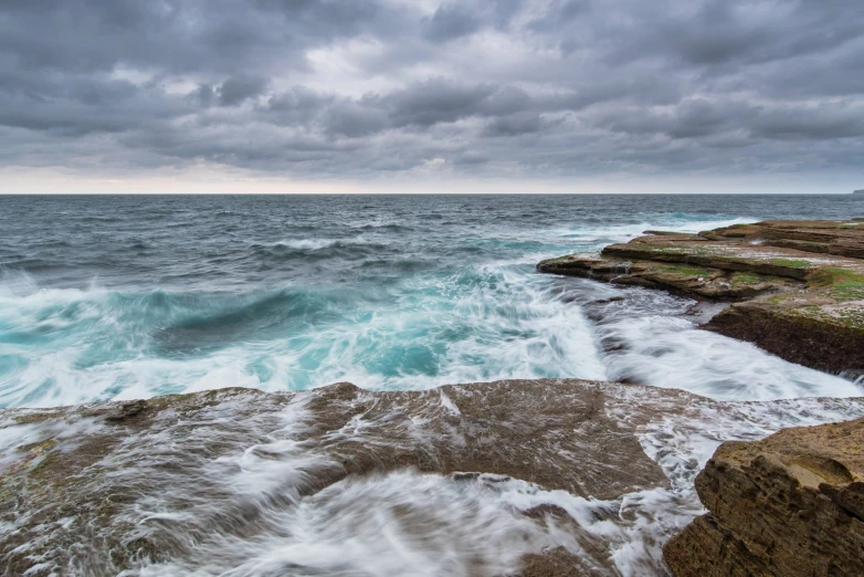 waves crashing on rocks with the sky in background