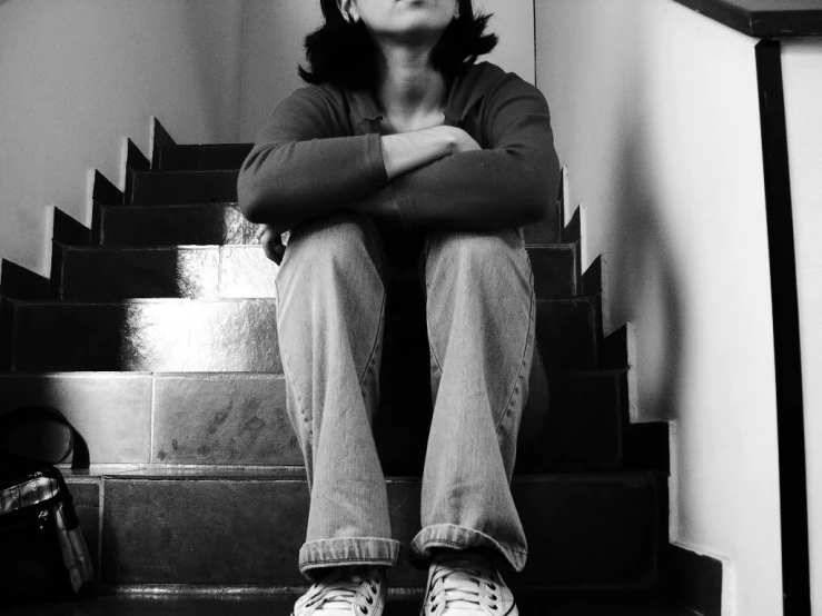 a woman with her head tilted looking upward while sitting on the steps