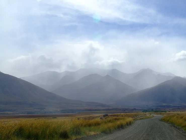 a road and field with mountains in the background