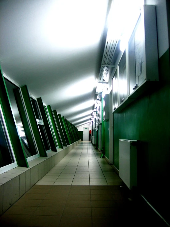 an empty hallway is lined with green, stainless - steel and tiled floor