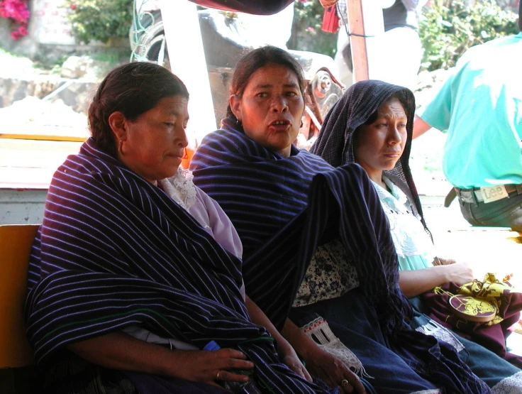 three women in different outfits and scarves sitting next to each other