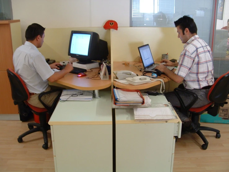 two men sitting at two desks on computers