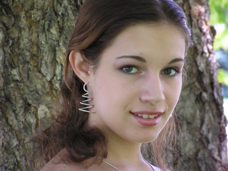 the woman is smiling while standing under a tree