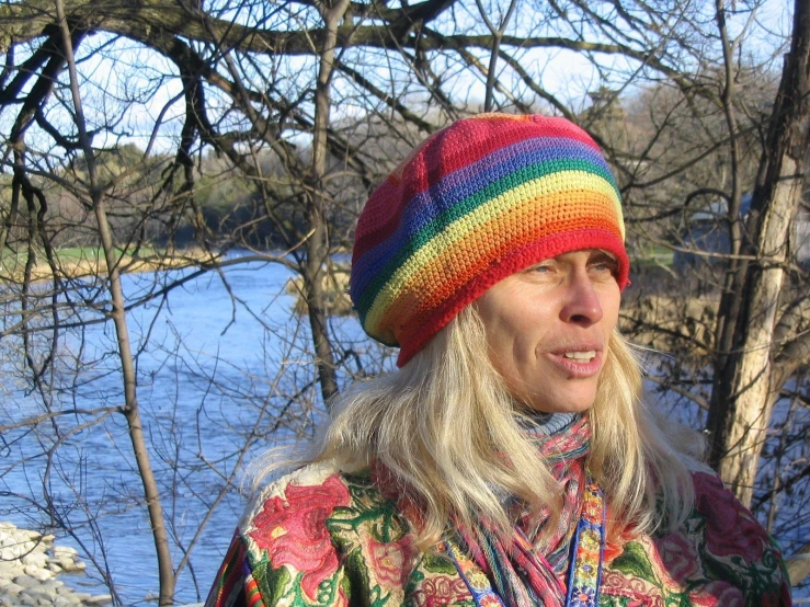 a blonde woman wearing a colorful hat with the lake in the background