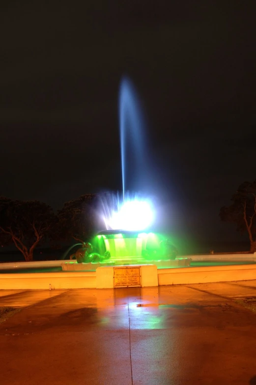 a fountain with bright lights shine on it at night