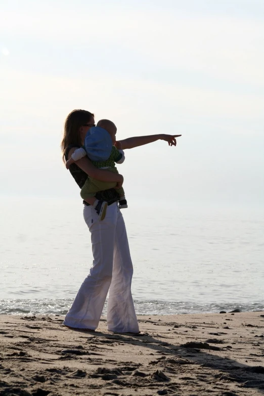 a woman and baby are standing on the beach