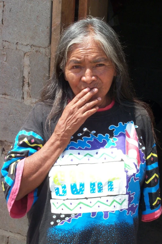 an old woman smokes a cigarette by a doorway