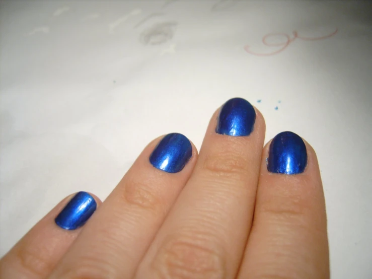 a person holding their hand up with a blue manicure