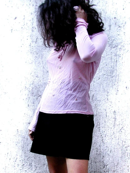 a person in a black and white skirt leaning against a wall
