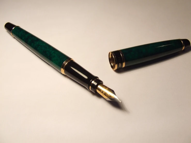 a green and black pen on a white surface