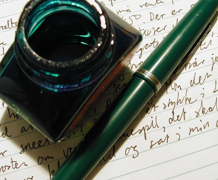 fountain pen with a green cover sitting on top of paper