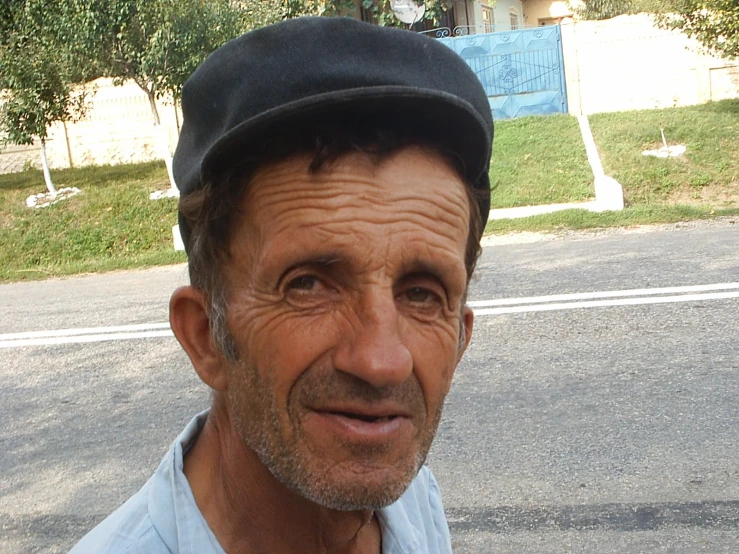 a man standing in the street near the corner wearing a hat