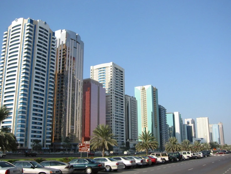 cars parked along the side of a street with tall buildings in the background