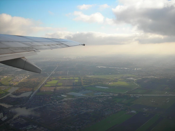 the wing of an airplane flying over a large country