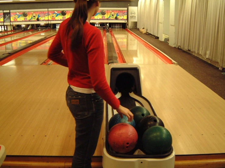 girl touching bowling balls in bowl