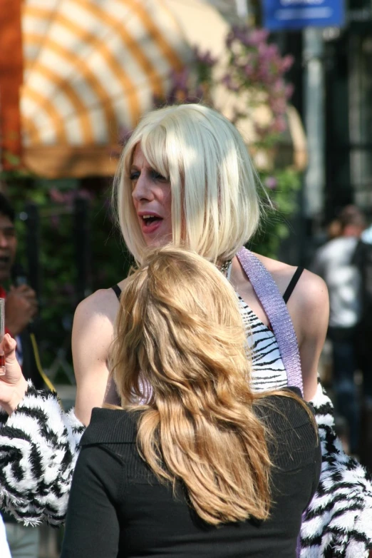 blonde woman in short hair using cell phone on sidewalk