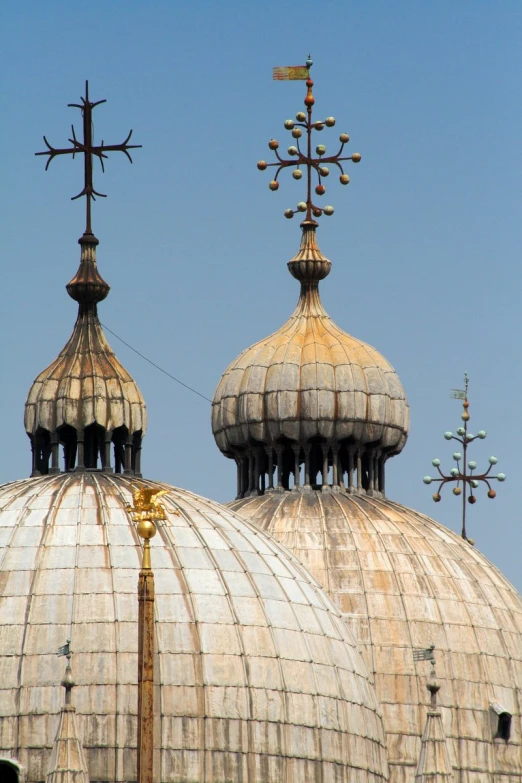 two towers in the back of a building with a weather vane on top