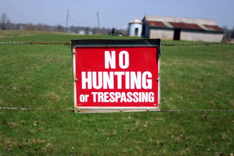 a sign hanging from a barbed wire fence that says no hunting or trespassing