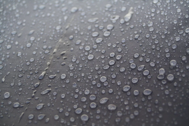 raindrops are laying down on the surface of a car