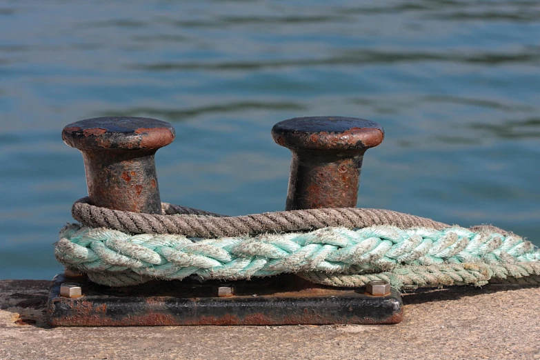 a roped and rusted metal post next to the water