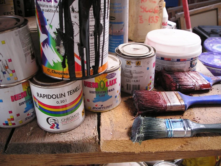 multiple paint cans on top of a wooden table