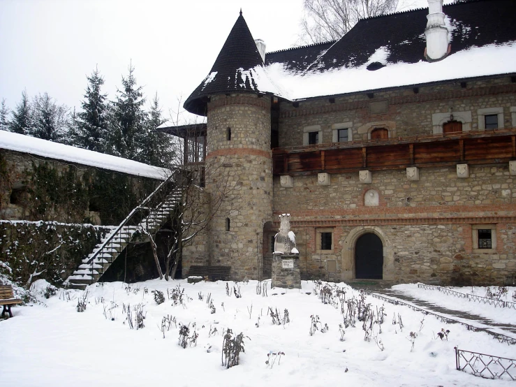 a castle with a snow covered lawn and bushes outside