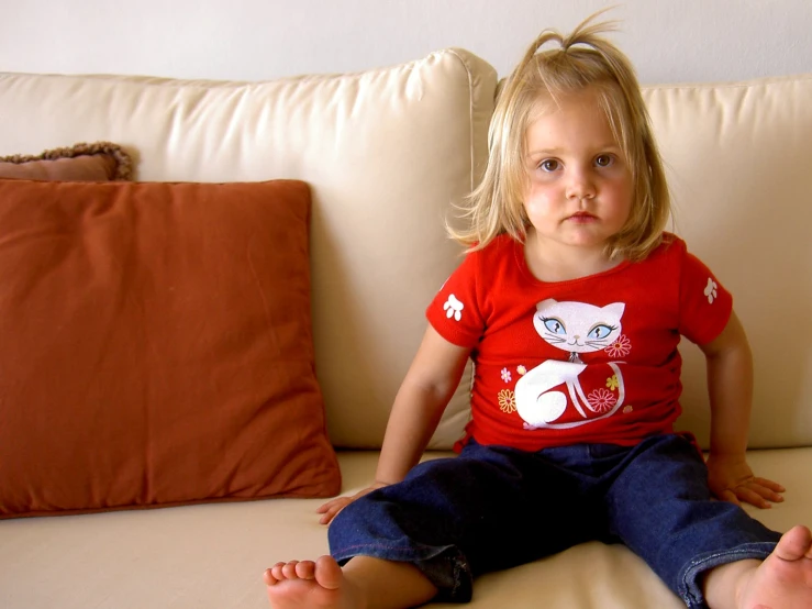  with blonde hair wearing red sitting on a couch