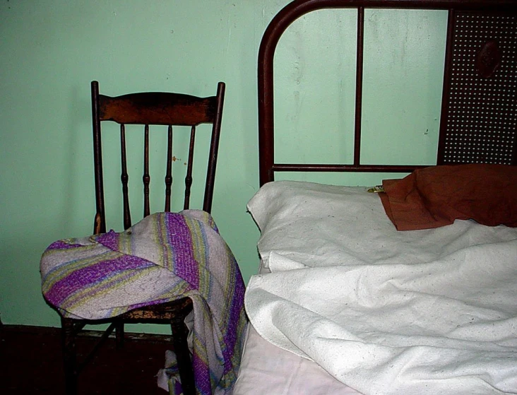 a chair and a bed with pillows and blankets