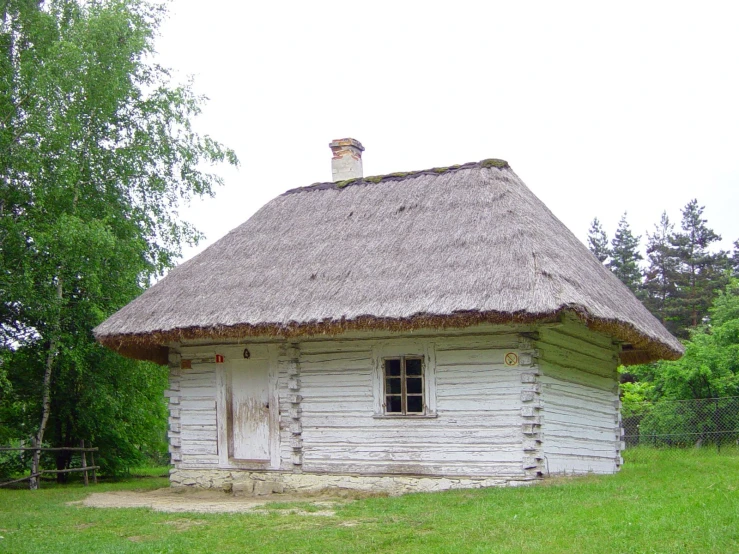 a small white cottage with a straw roof