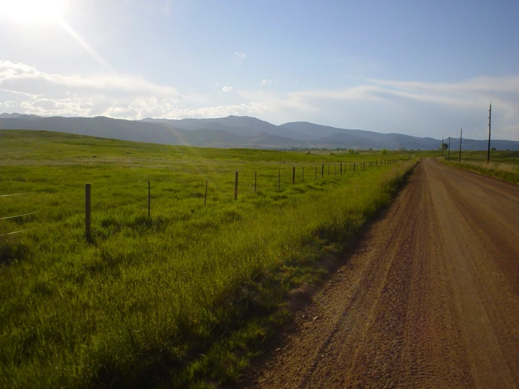 a country road on the side of a grassy hill