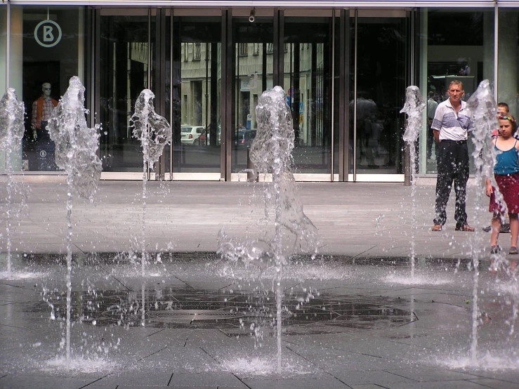 people are looking at a large fountain with water spouting it