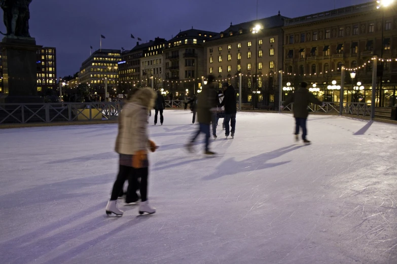 a group of skateboarders ride in the snow on a night rink