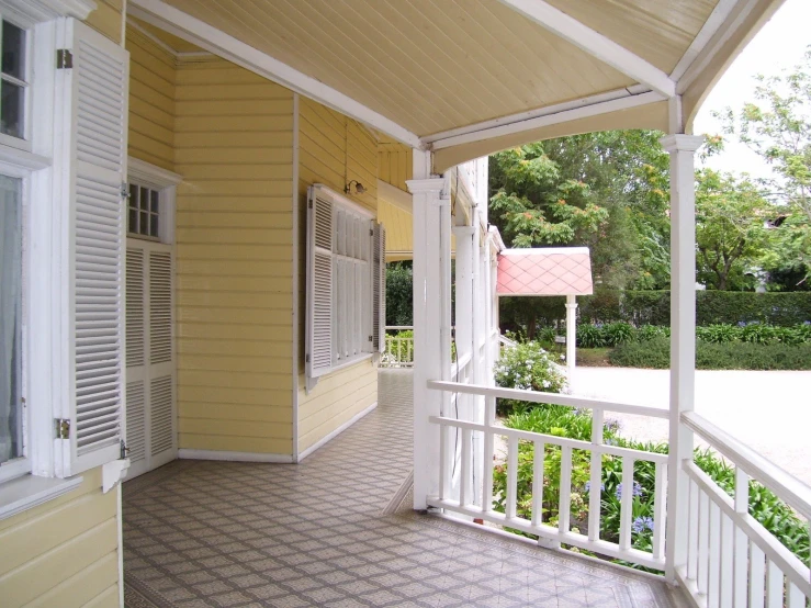 a large yellow porch with a white railing