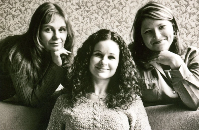 three women are posing for the camera on the couch