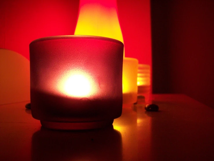 a lit candle and two jars on a table