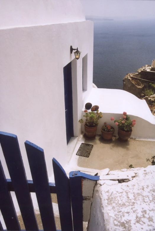 the white building with two blue doors has pots full of flowers