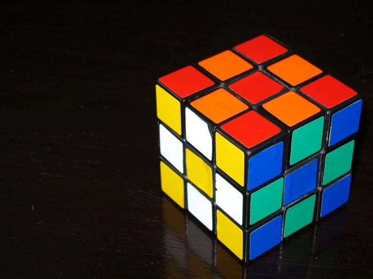 a cube shaped toy sits on a black surface