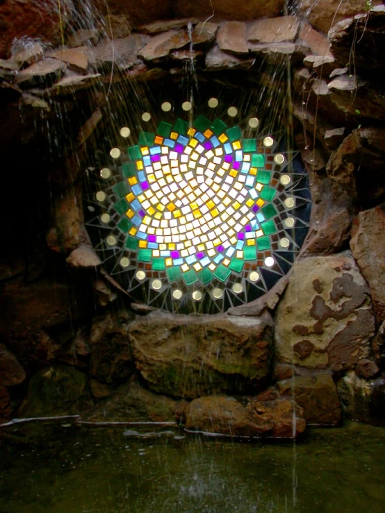 a colorful mirror mosaic set in the rocks by a stream