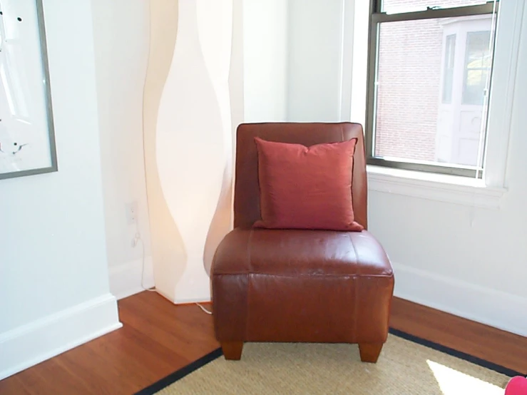 the red leather chair is facing a big window