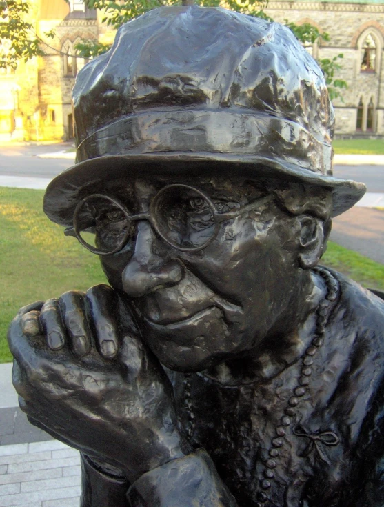 a statue with glasses, wearing a hat and chain, is looking off to the side