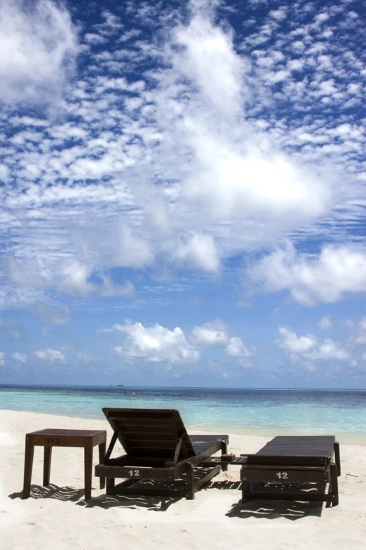 three lawn chairs sitting on the sand by the ocean