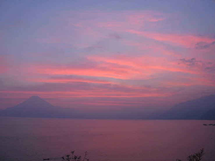 a sunset over the ocean with a view of mountains