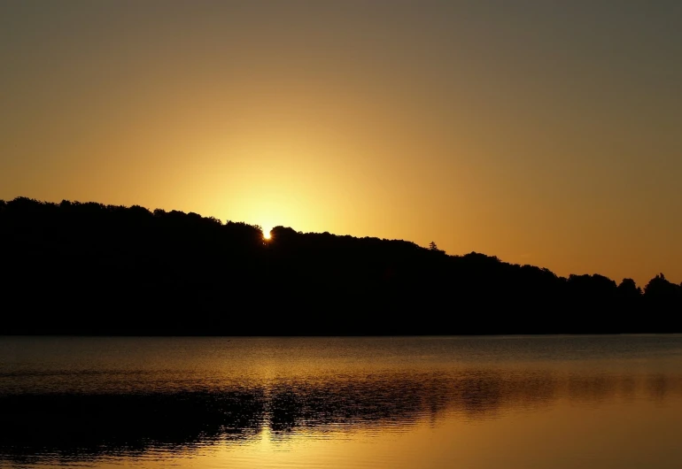 sun shining over the hills with reflections on water