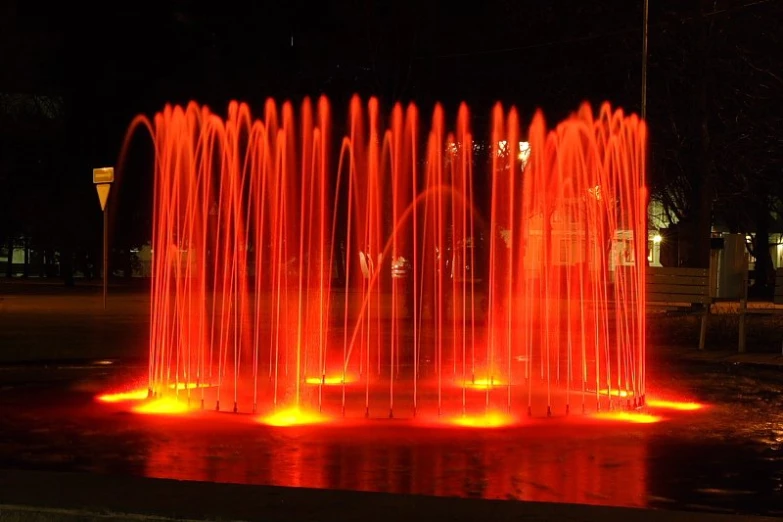 a very bright red fountain in a large park