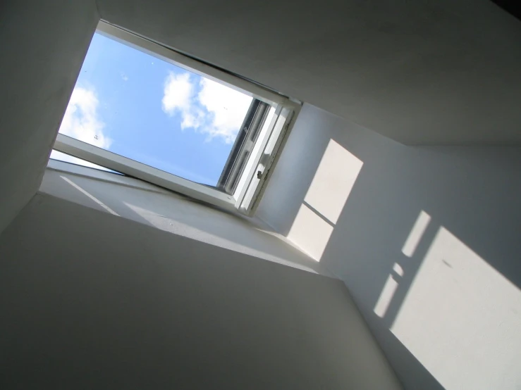 a white room with a window on the inside and the sky in the back