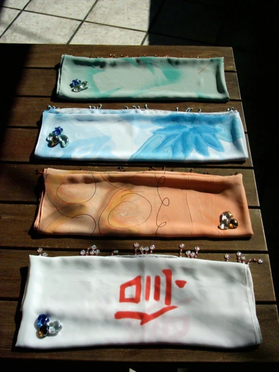 three different colored satin bags laying on a wooden surface