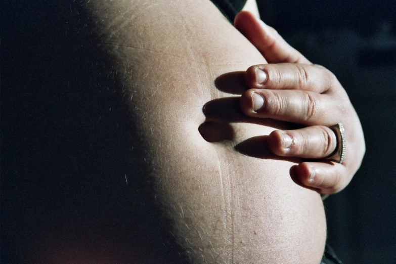 a closeup of a belly with two hands and a ring